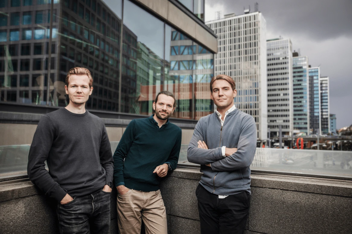 Atlar's three co-founders standing together on a rooftop overlooking a city