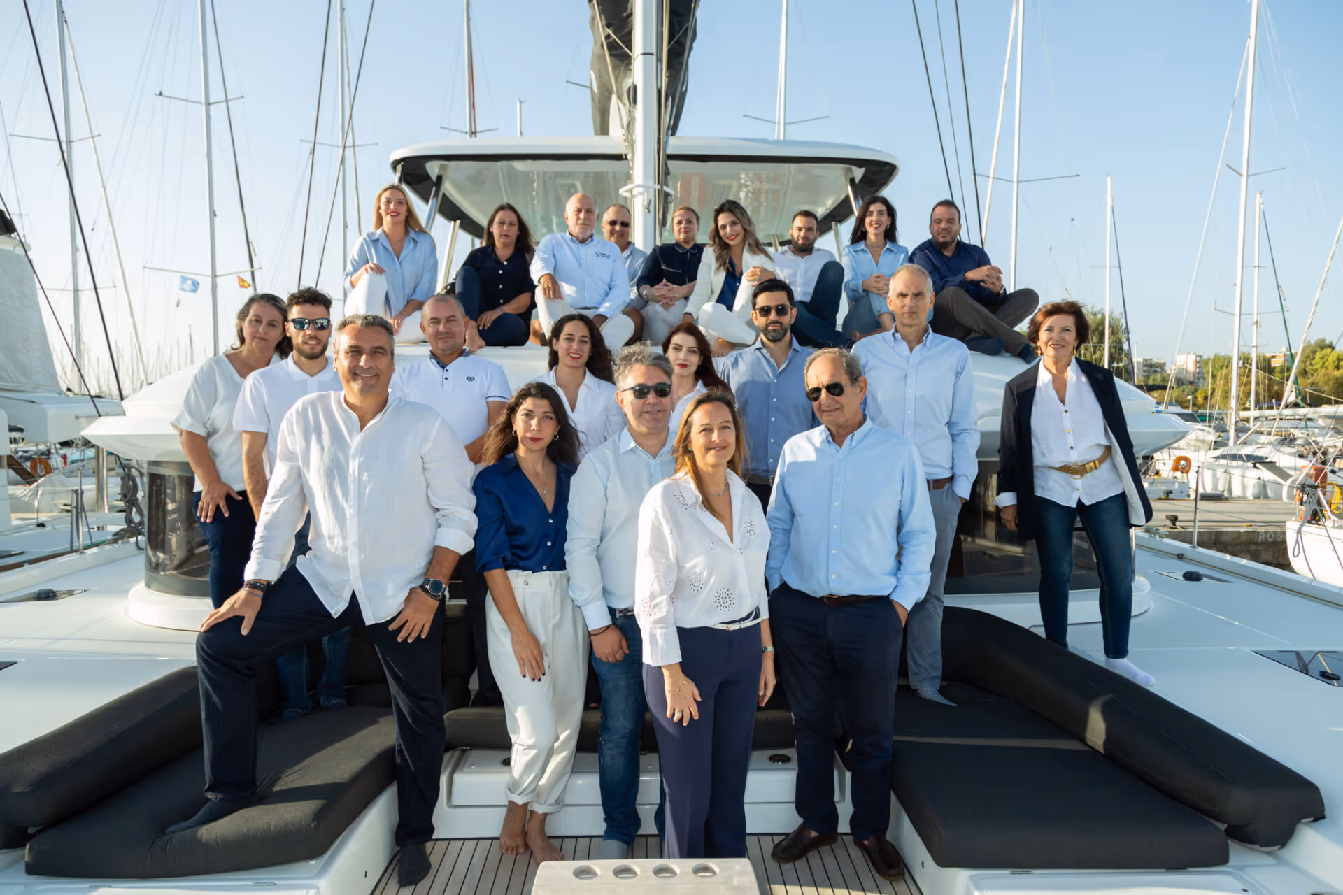 A group of people stands and sits on a boat, posing for a group photo.
