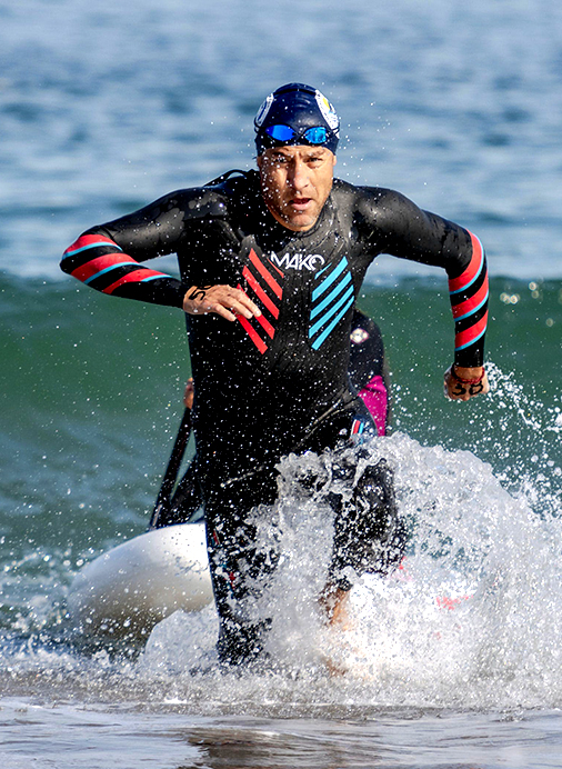 Triathlete wearing a pink a swim cap and jumping out of the pool