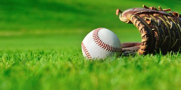 A baseball and glove on an outfield