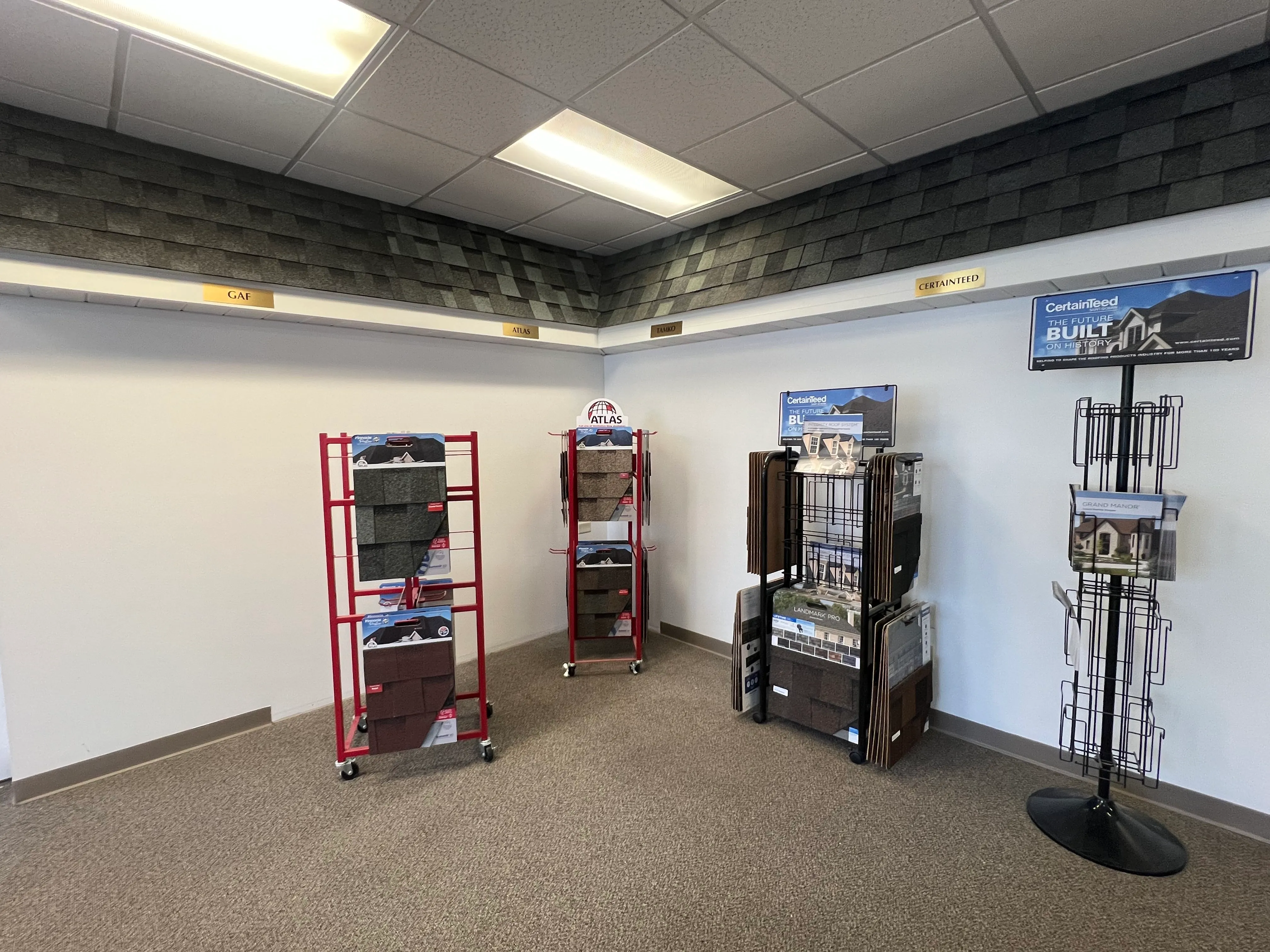 Tip Top Roofing & Siding showroom displaying roofing shingle samples from GAF, Atlas, Tamko, and CertainTeed brands.