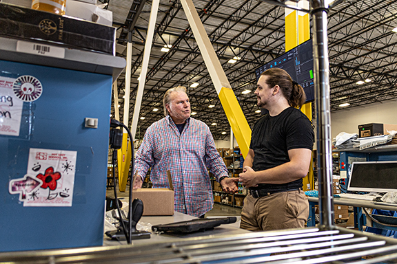 Warehouse manager and worker talking at factory distribution center