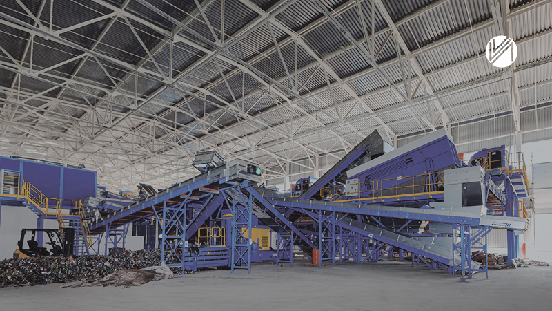 Large industrial recycling conveyor system with blue metal structures inside a spacious warehouse.