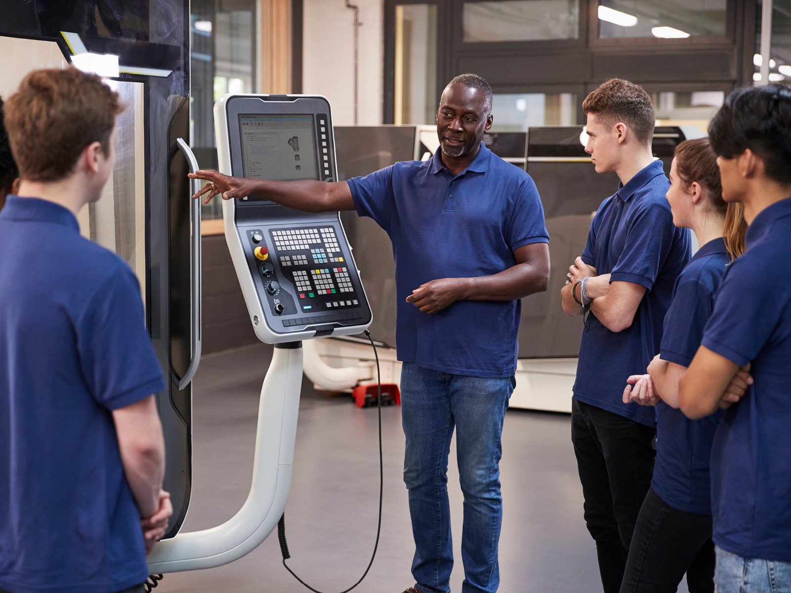 Instructor demonstrating a CNC machine to a group of learners