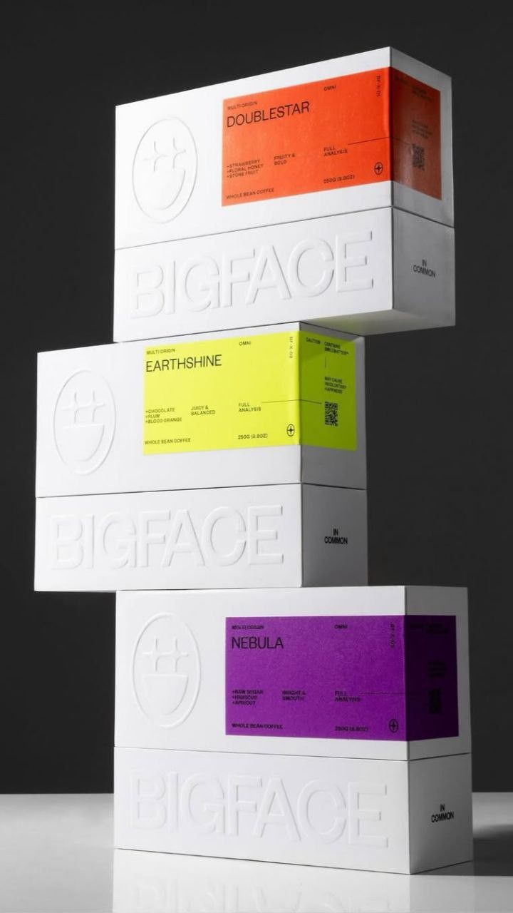 Three stacked white Bigface coffee boxes with orange, yellow and purple accent panels