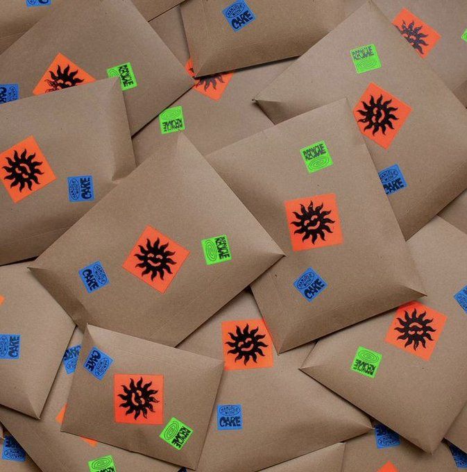 Scattered kraft paper envelopes sealed with orange sunburst and green branded stickers