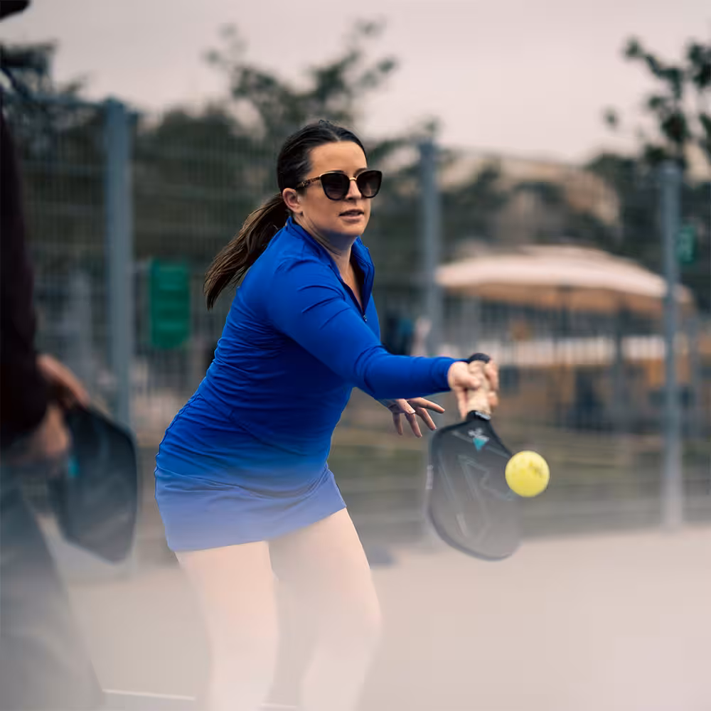 a woman in blue clothes hitting a low forehand volley
