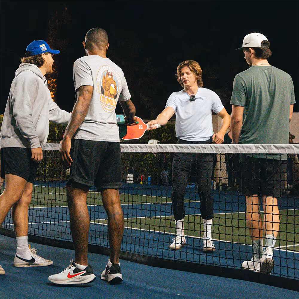 four players paddle tap at the end of a pickleball match
