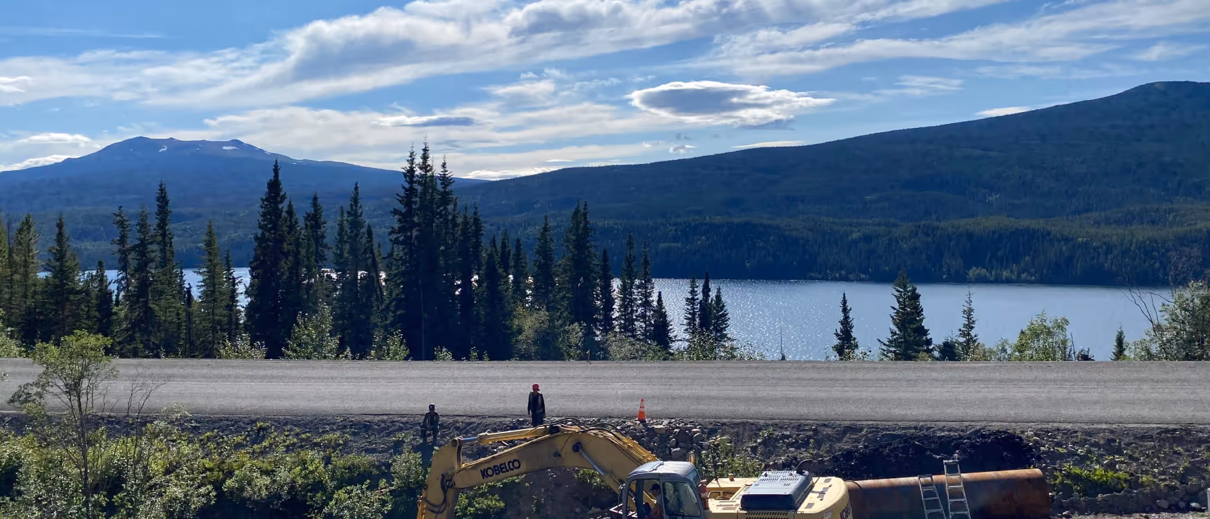 working on a construction site across from a body of water in the mountains
