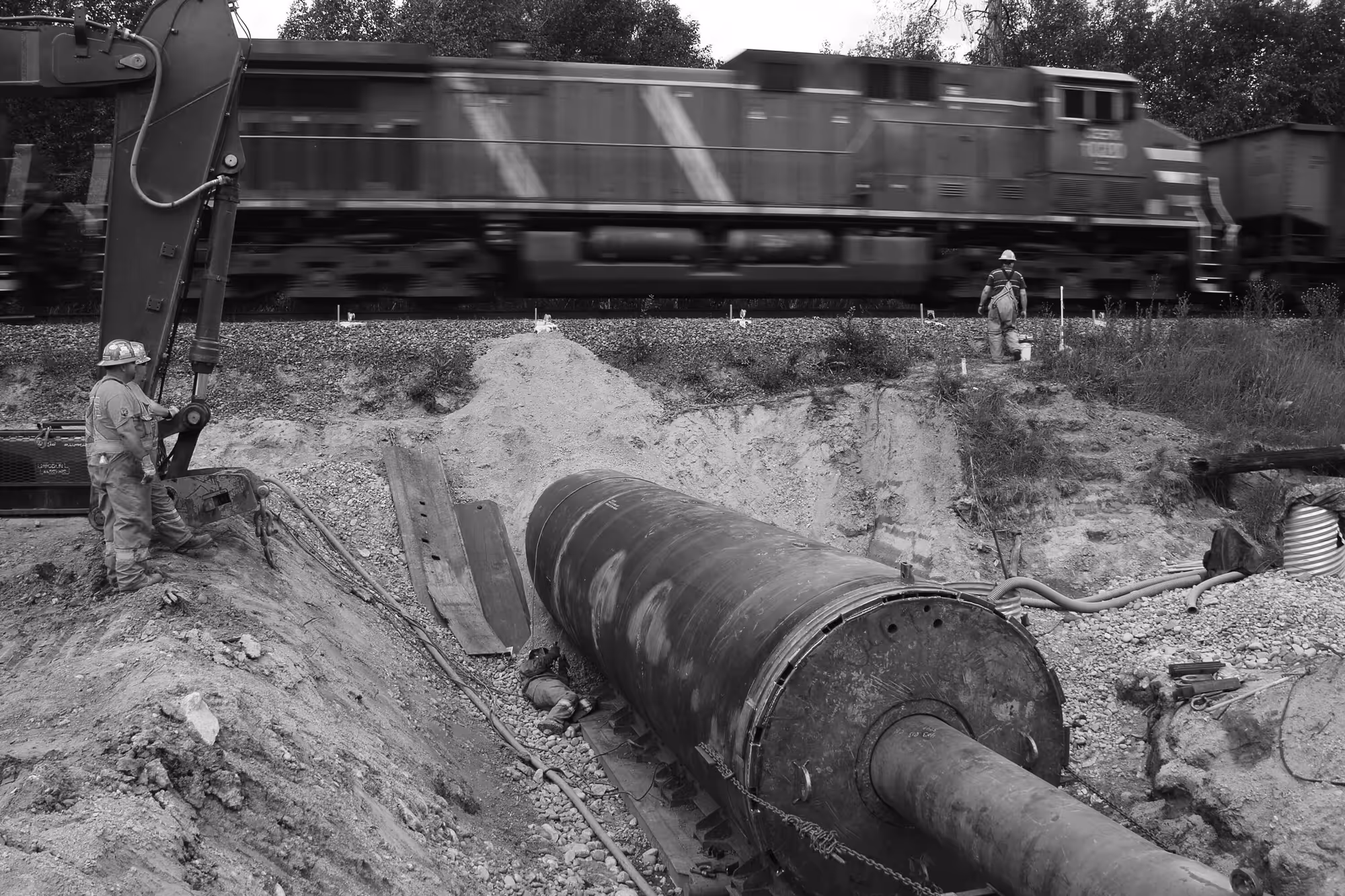 a pipeline being pushed through earth underneath a rail line