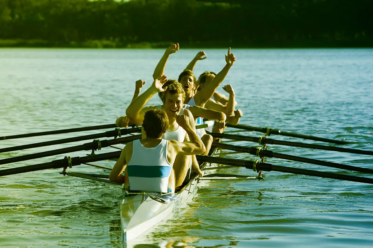 Juichende roeiers een een sportieve roeiboot. 4 persoons met stuurman.