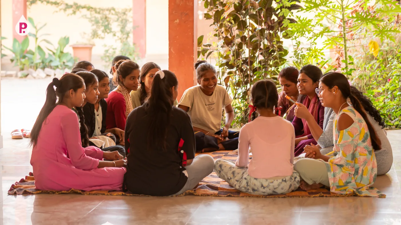 Girls seated in a circle at an outdoor Pinkishe session in Sakti, Chhattisgarh