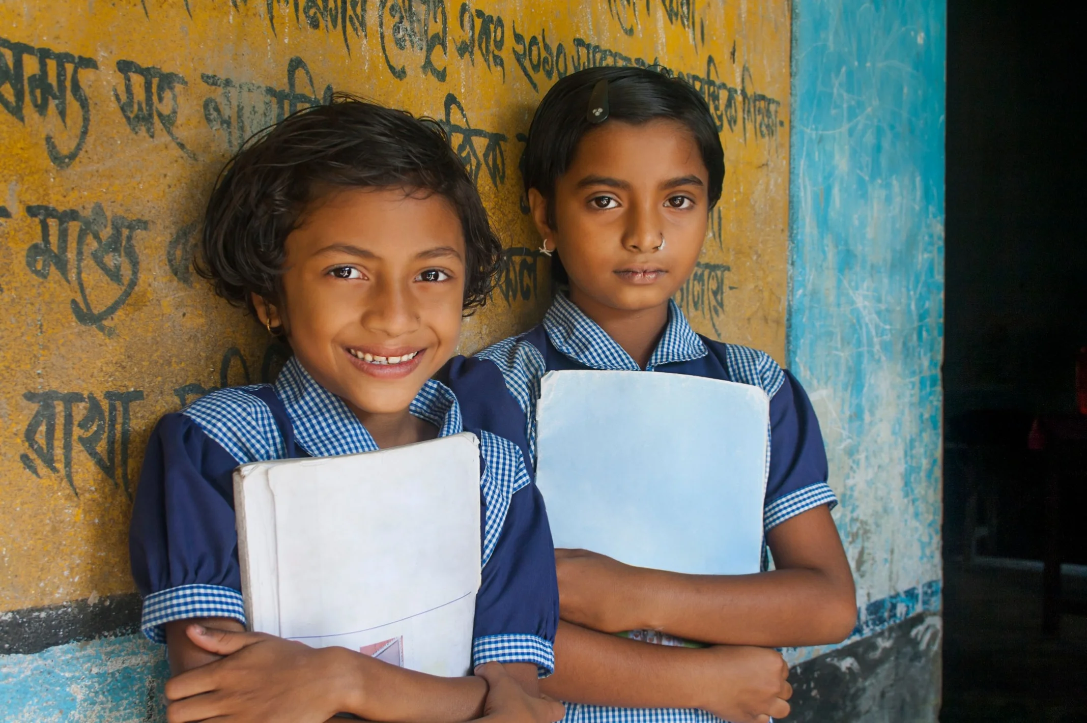 Two schoolgirls holding their notebooks