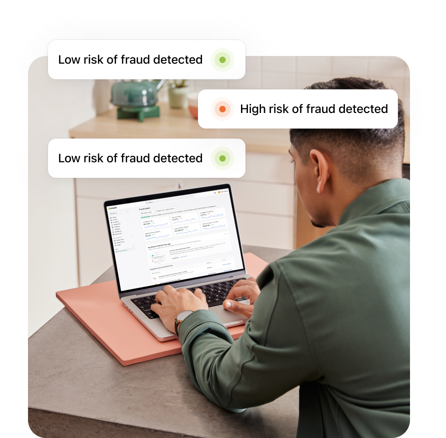 Shopify merchant sitting at a desk with a laptop and receiving notifications of low-risk and high-risk fraud.