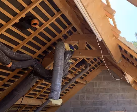 Photo de l'installation d'une gaine de VMC isolée dans la toiture d'un logement en rénovation