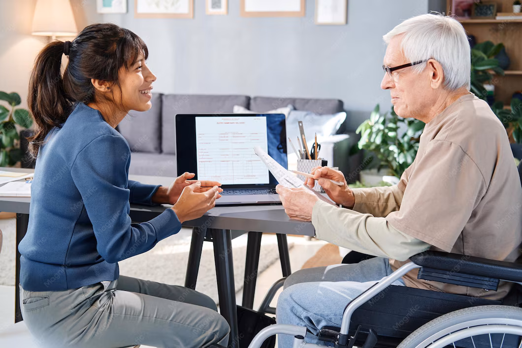 Un homme senior en fauteuil roulant s'entretient avec une conseillère d'Aid'habitat pour l'adaptation de son logement