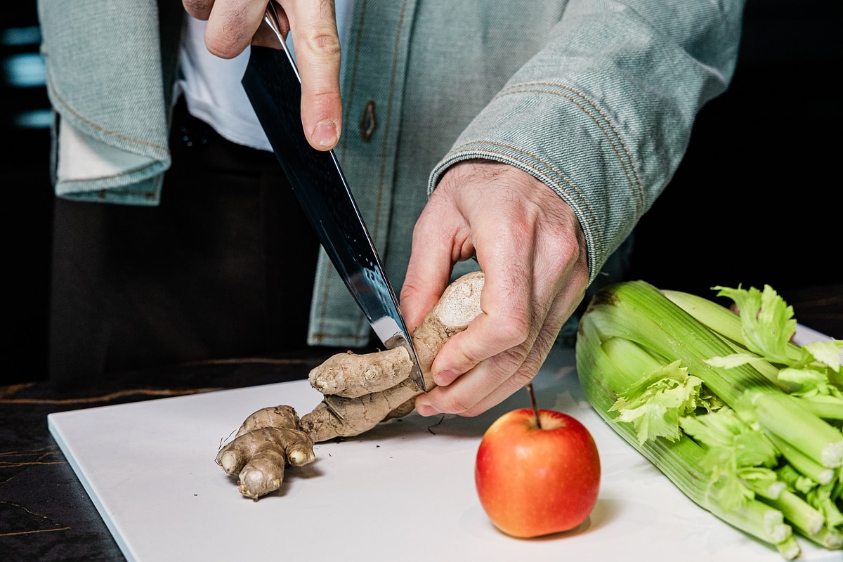Zubereitung frischer Zutaten mit Ingwer, Apfel und Sellerie auf einem Schneidebrett