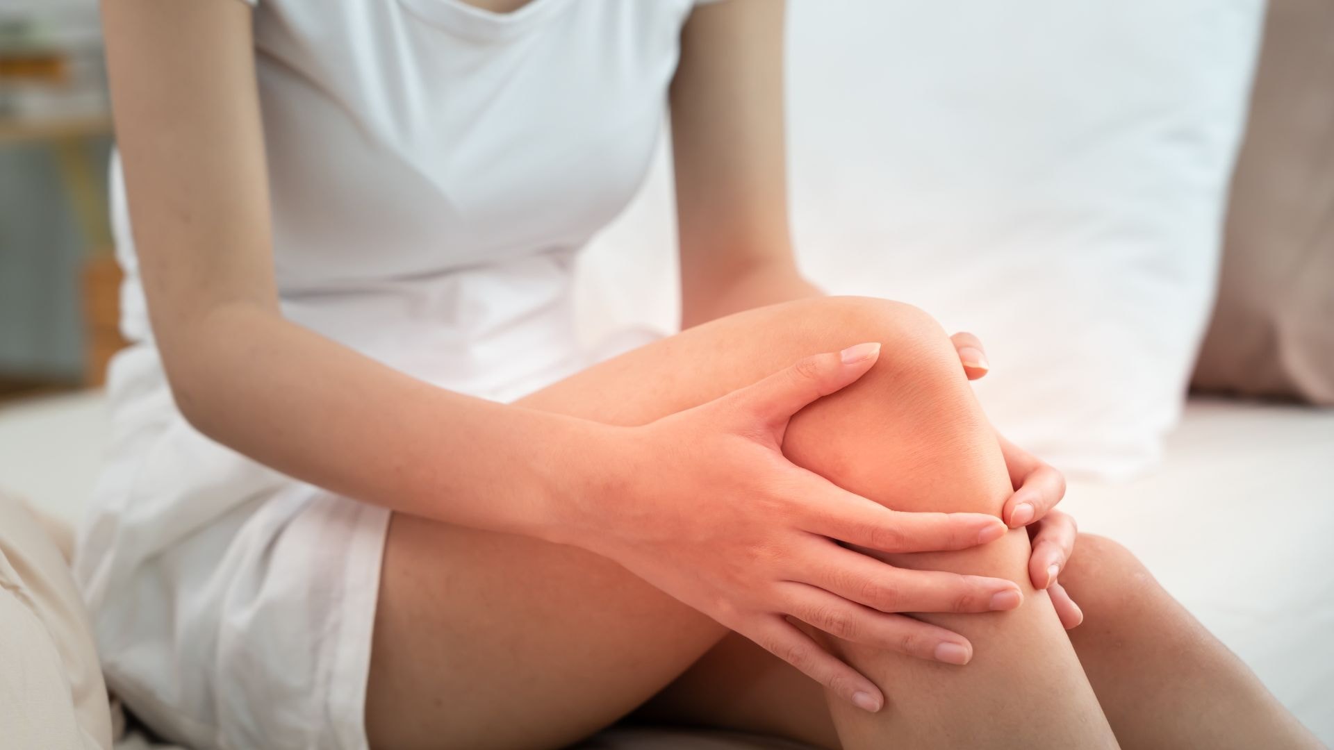 Eine Patientin hält sich schmerzgeplagt das Knie – Darstellung von Symptomen bei Arthrose im Knie (Gonarthrose) und Behandlungsbedarf in der spezialisierten Schmerztherapie.