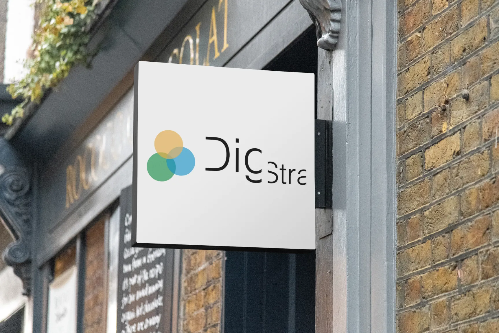 DIGSTRA-logoen montert på fasaden til kontorbygget i Sandnes sentrum. Bildet viser inngangspartiet med moderne skilt og glassdør i et bymiljø med naturlig lys og refleksjoner.