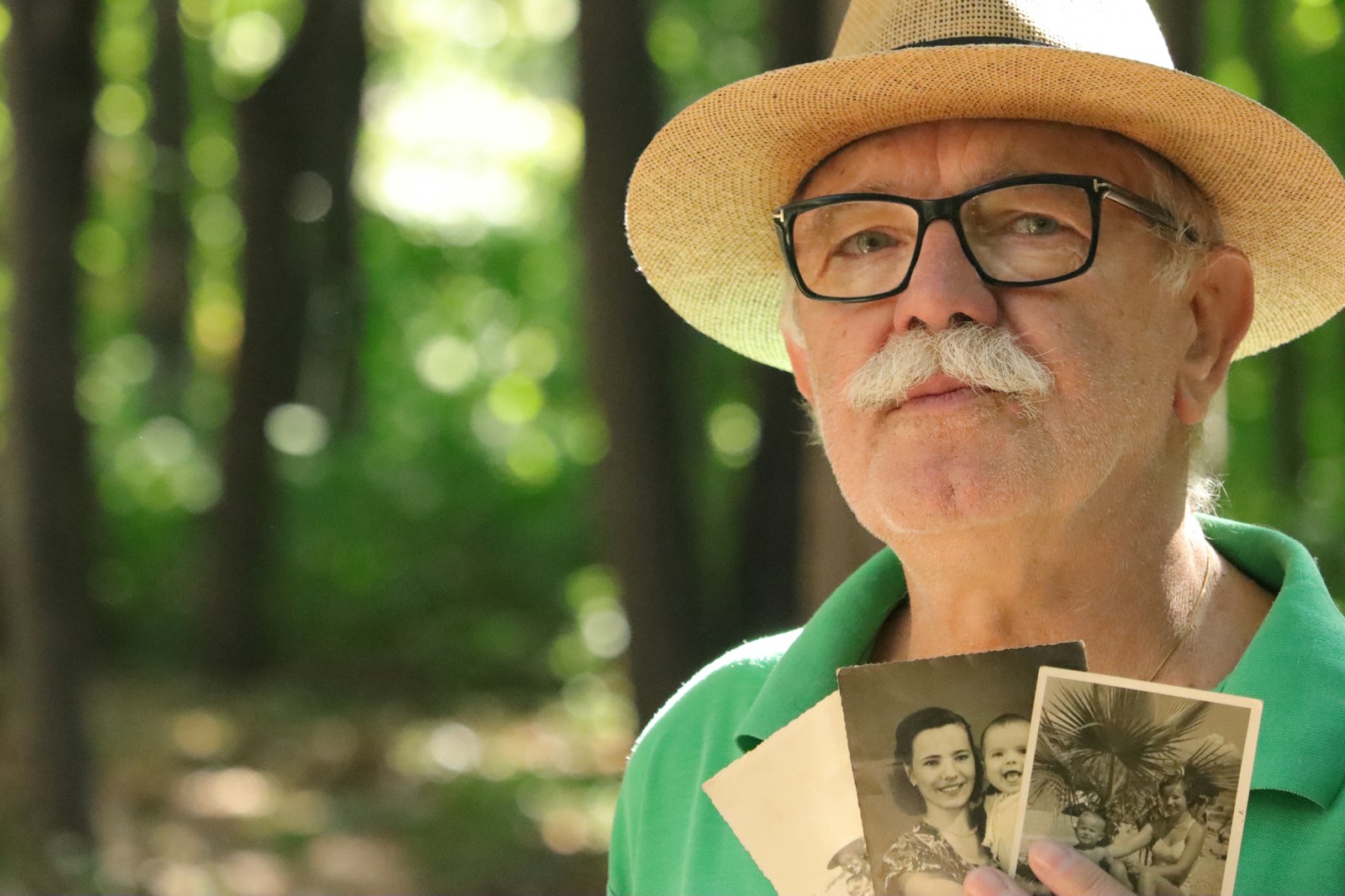 a man in a hat and glasses holding up a picture of a woman