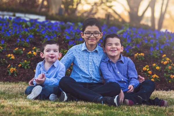 a couple of kids sitting on top of a grass field