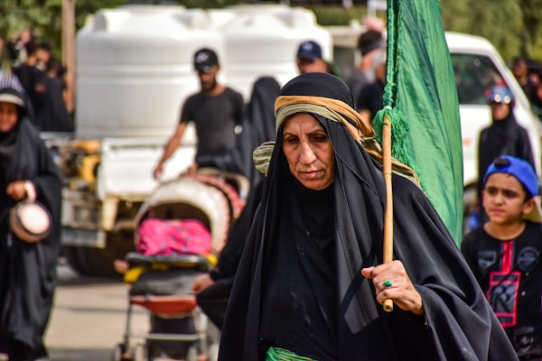 woman in black hijab holding green stick