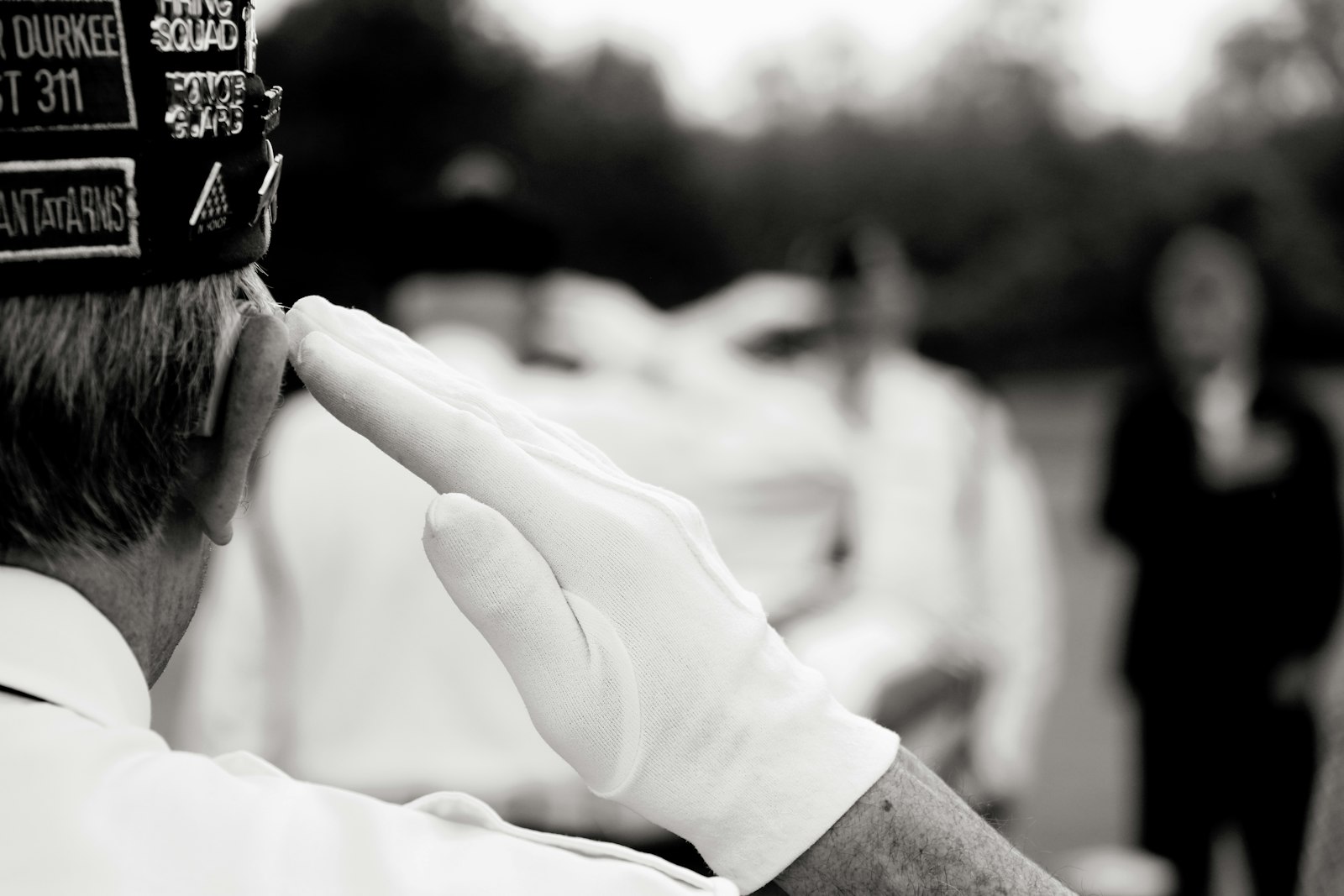 Veteran saluting at a ceremony with blurred figures