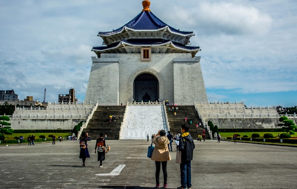People walk towards a large monument with blue roof.