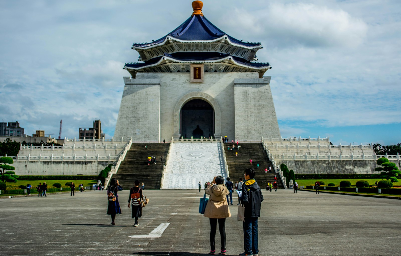 People walk towards a large monument with blue roof.