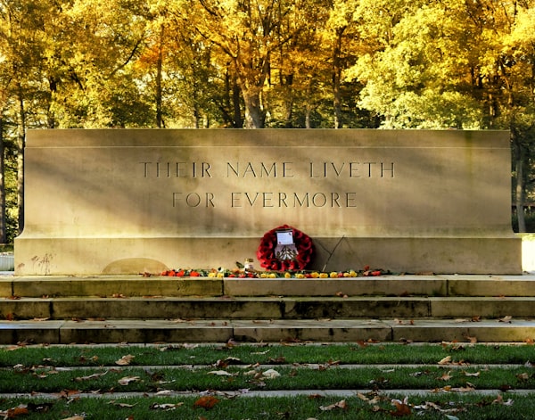a stone wall with a statue on it and trees in the background