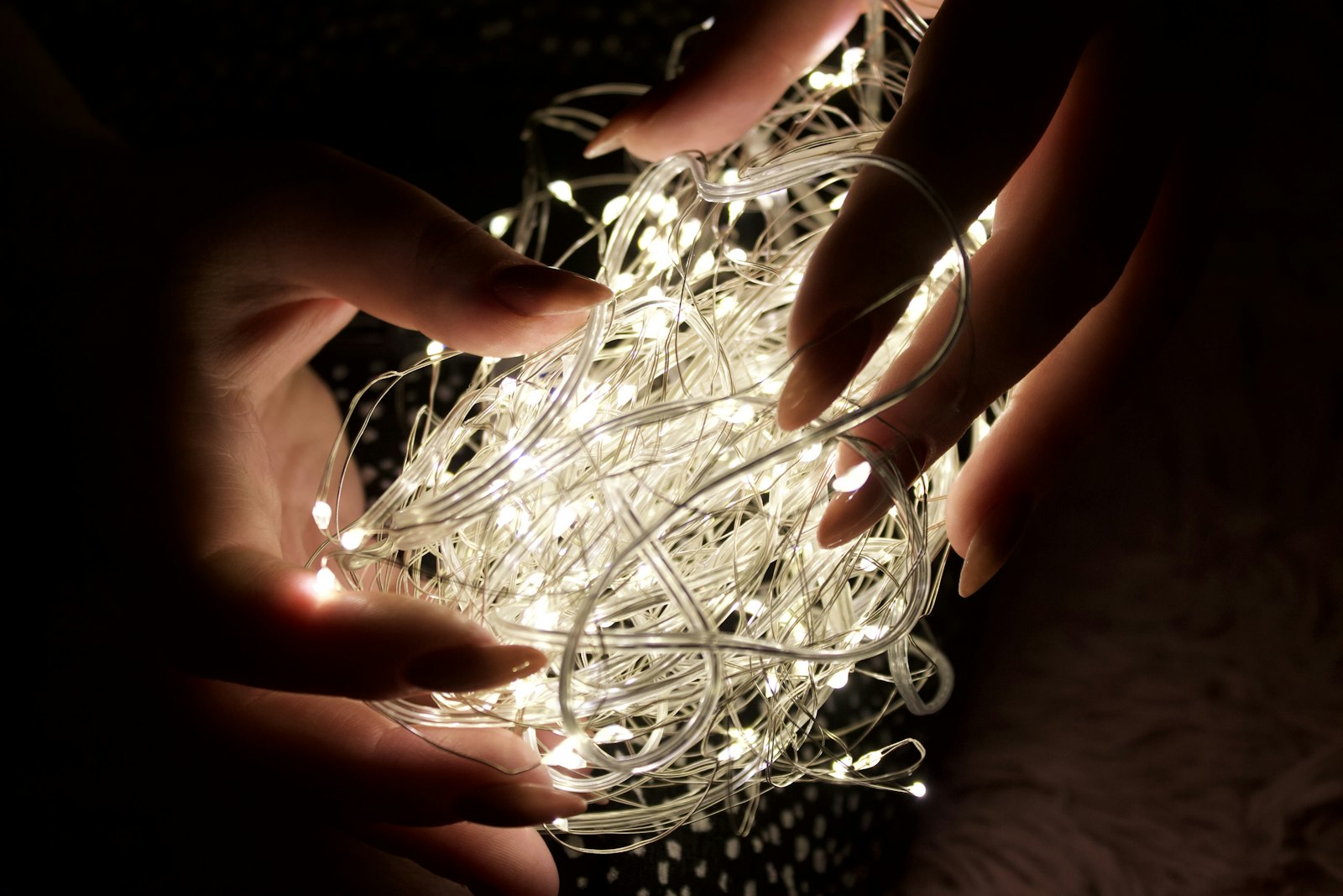 Hands holding a tangled ball of fairy lights