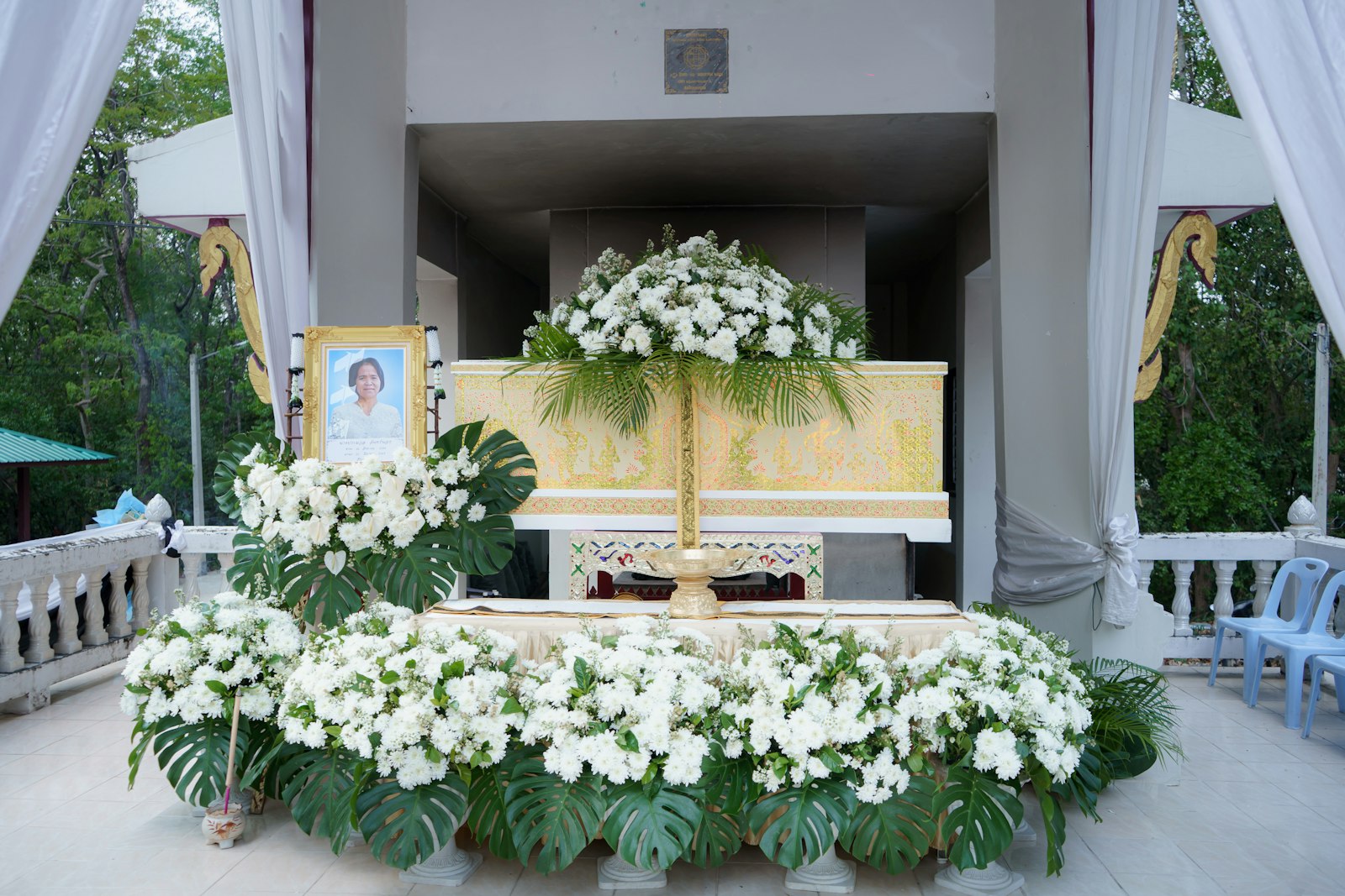 A funeral altar decorated with white flowers and a portrait