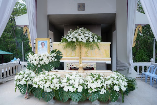 A funeral altar decorated with white flowers and a portrait
