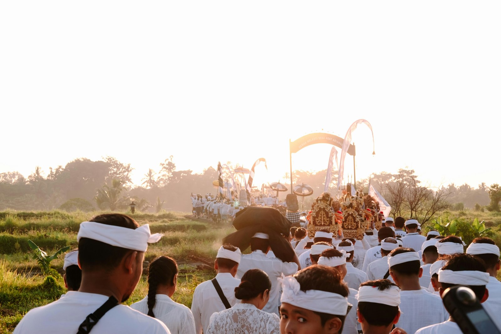 Procession of people in white attire with ornate carriage