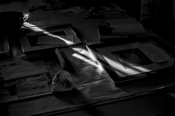Sunlight streams across a table of papers and frames