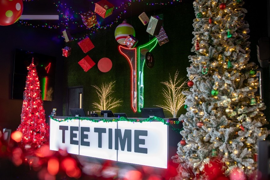 Celebrate New Year’s Eve at TeeTime in Webb City with heated golf bays, drink specials, and Route 66 vibes. Open 4–7 PM for your last swing of 2025. Photo shows festive TeeTime Checkin Desk