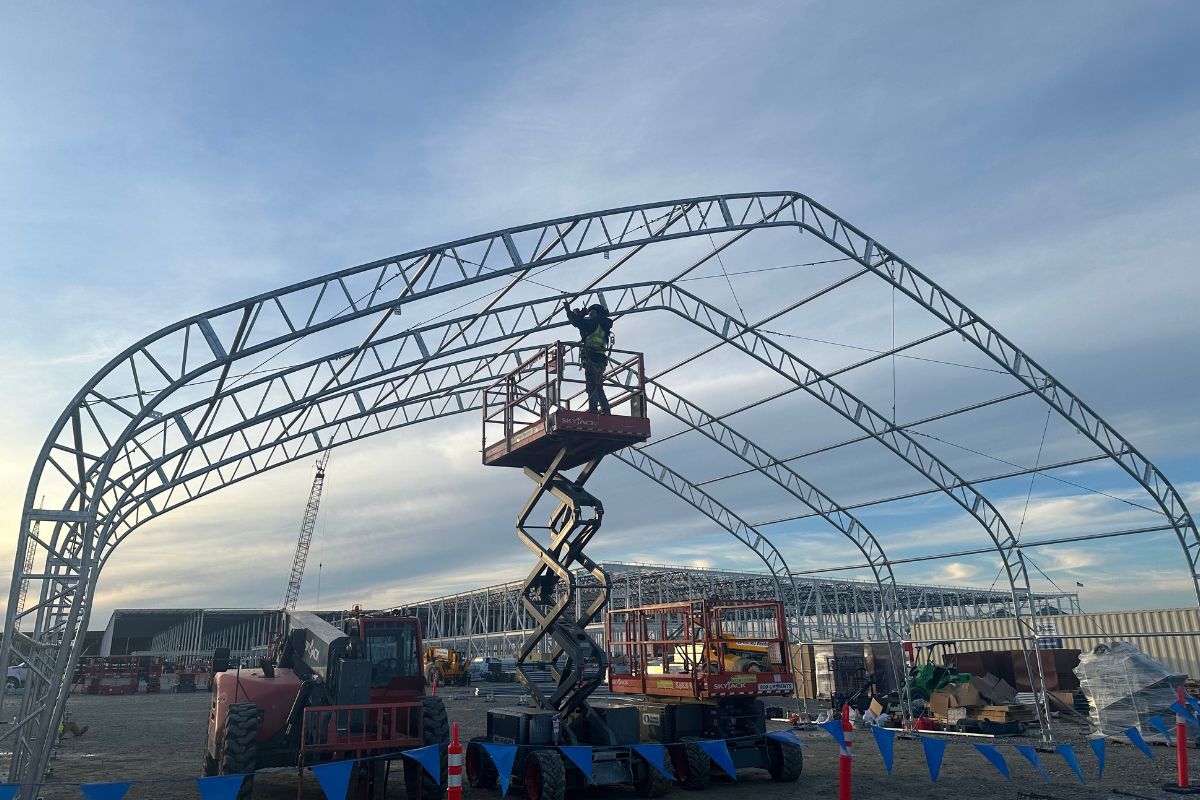 ACC Rental crew assembling a large clear-span structure on an industrial job site