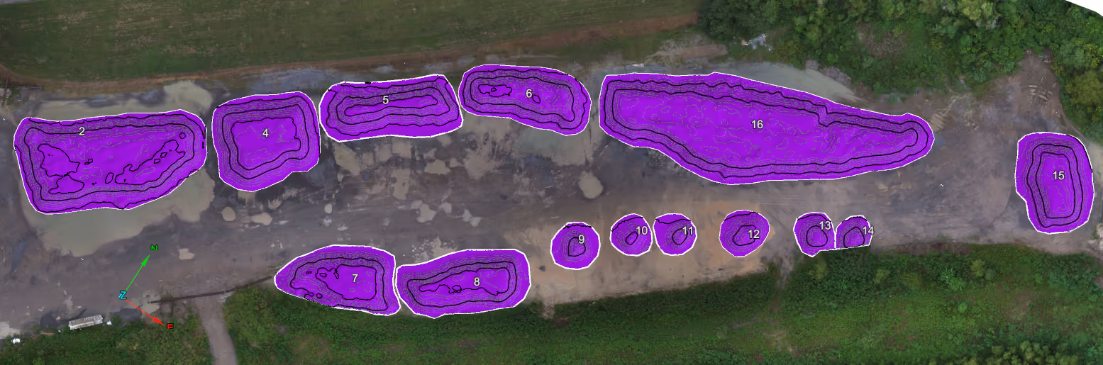 Aerial view of a site with 14 labeled purple contour-mapped areas on cleared land with surrounding greenery.