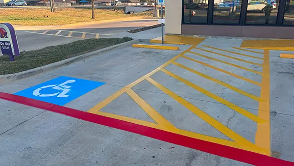 An ADA parking stall with a yellow access aisle and red fire lane.