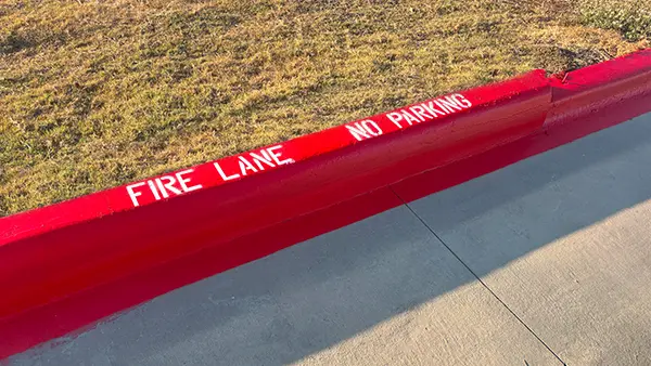 A freshly painted red fire lane with "FIRE LANE NO PARKING" text.
