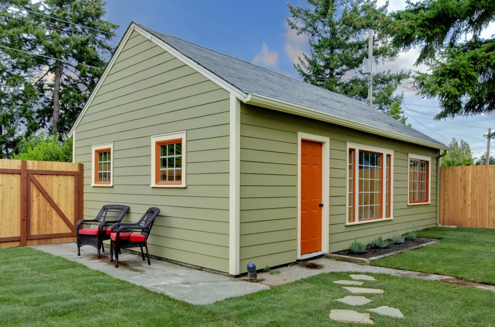 small guest house cabin with green vinyl siding and wooden doors and window trims