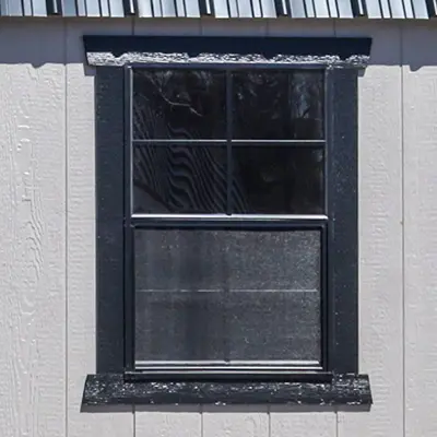 Black-framed rectangular window on beige textured exterior wall with divided glass panes.