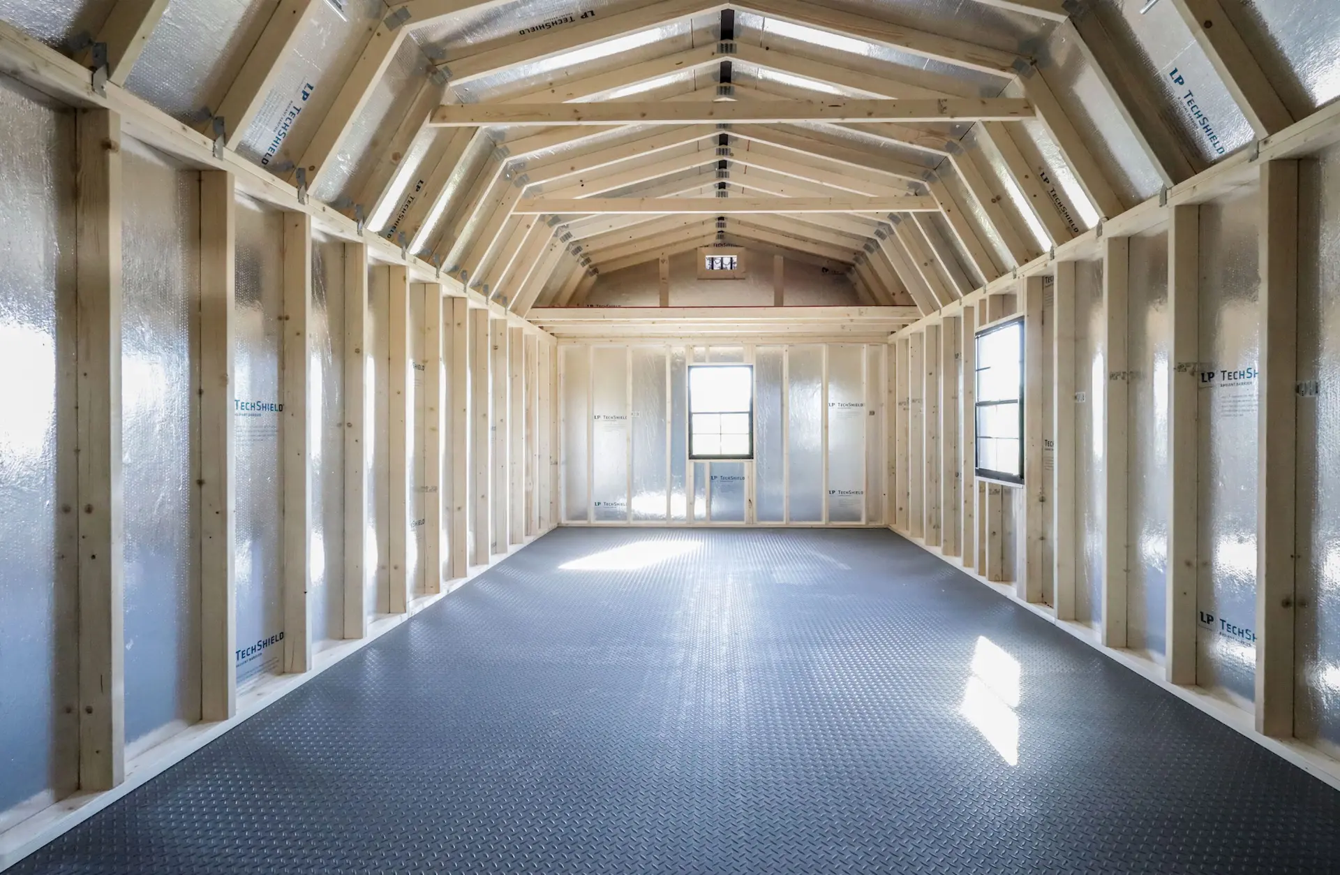 inside view of the columbus shed model, with rubber flooring, 2 windows, and an overhead shelf