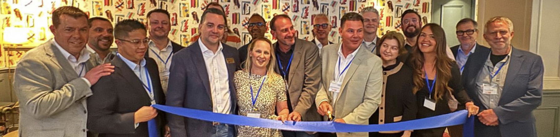 A group of people in suits cut a long blue ribbon.