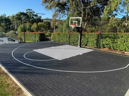 Black basketball court in a backyard setting