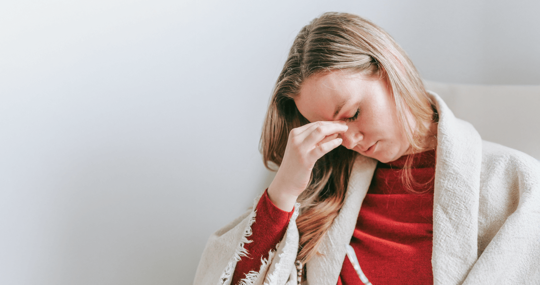 Woman closing her eyes in discomfort due to burning eyes, a common reason for visiting an optometrist. 