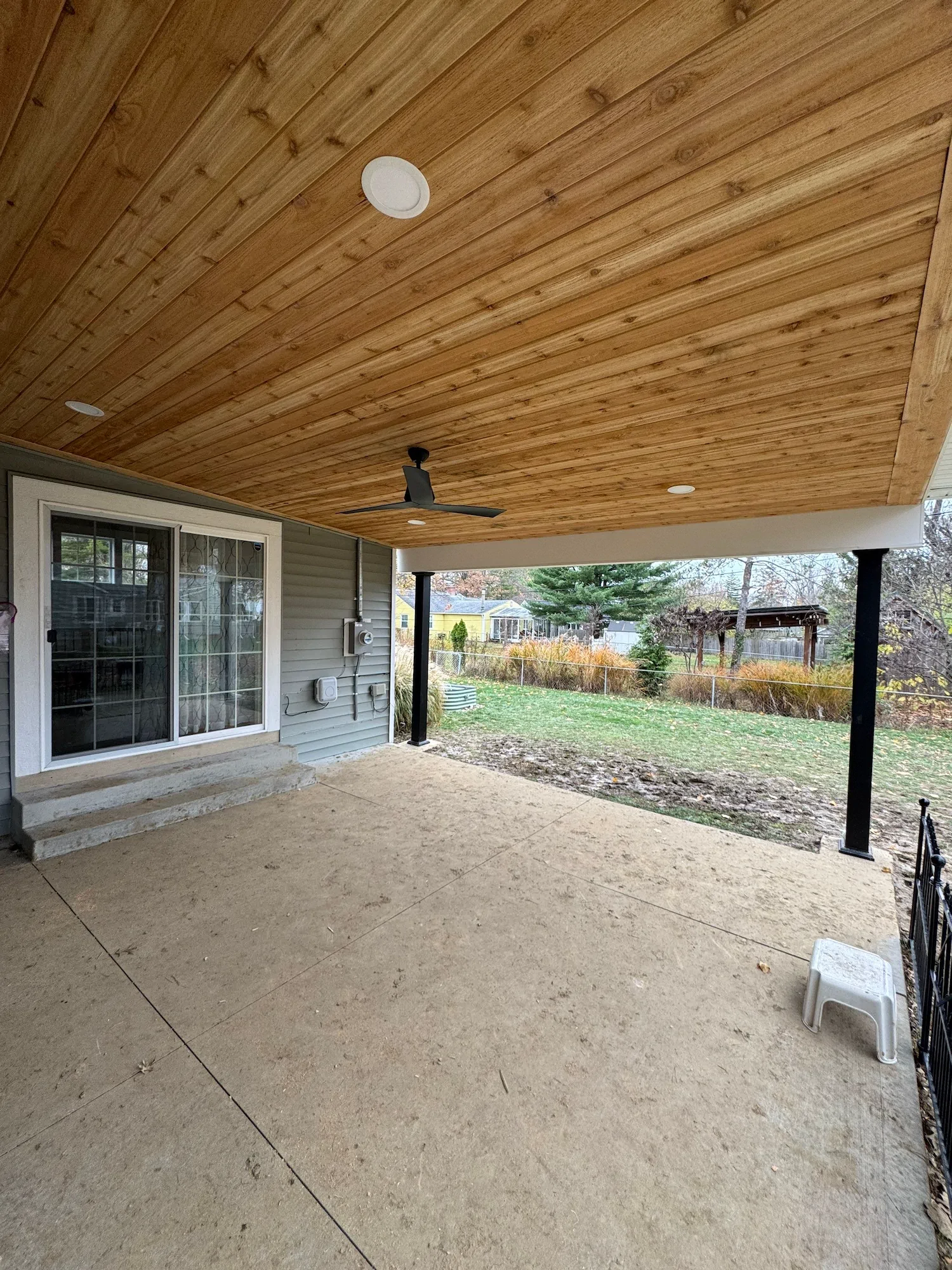 A custom patio renovation job with a natural wood ceiling and outdoor ceiling fan.