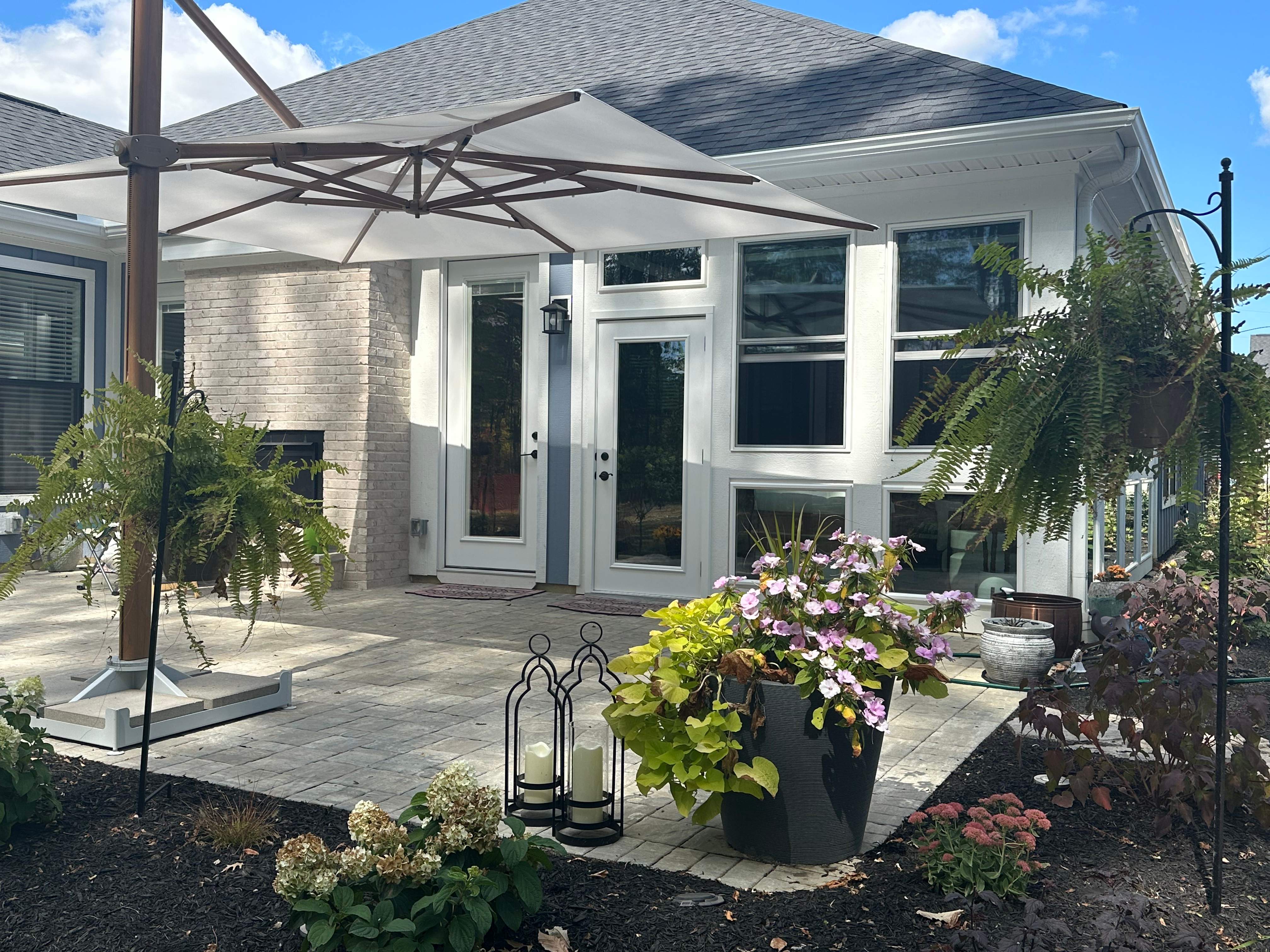 An outdoor patio with a patio umbrella and plants.