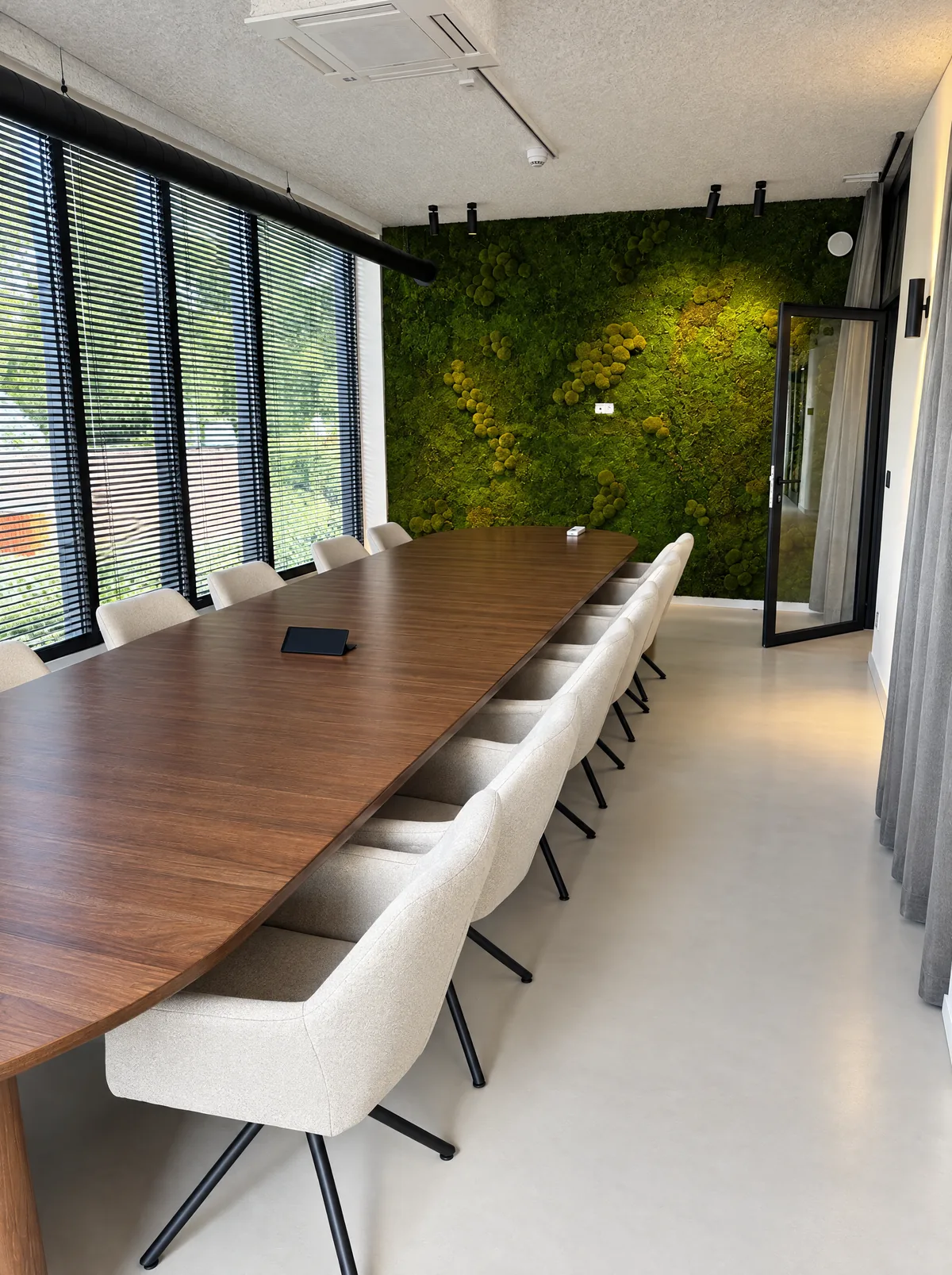 Vergaderzaal in Schilde met houten tafel, lichte stoelen en groene moswand