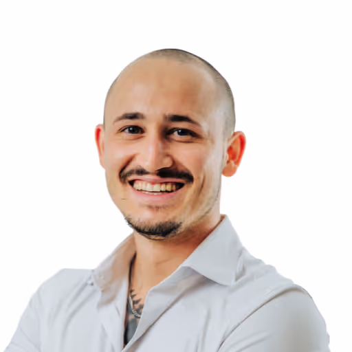 Porträt eines lachenden Mannes mit kurzem Haar und weißem Hemd vor weißem Hintergrund.